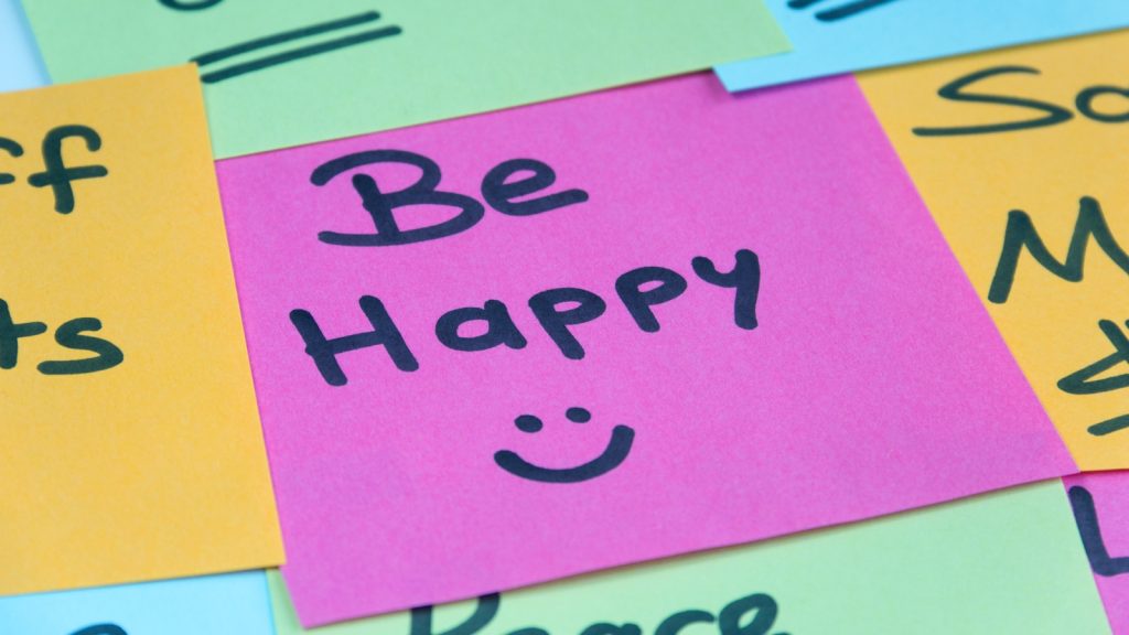 A post it showing the message 'Be Happy :)'