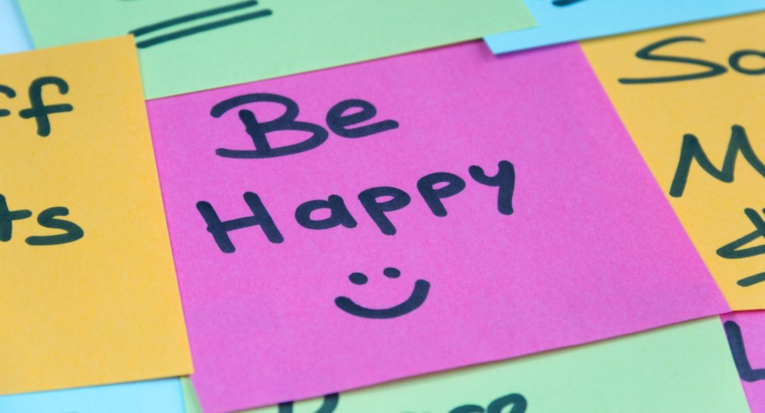 A post it showing the message 'Be Happy :)'