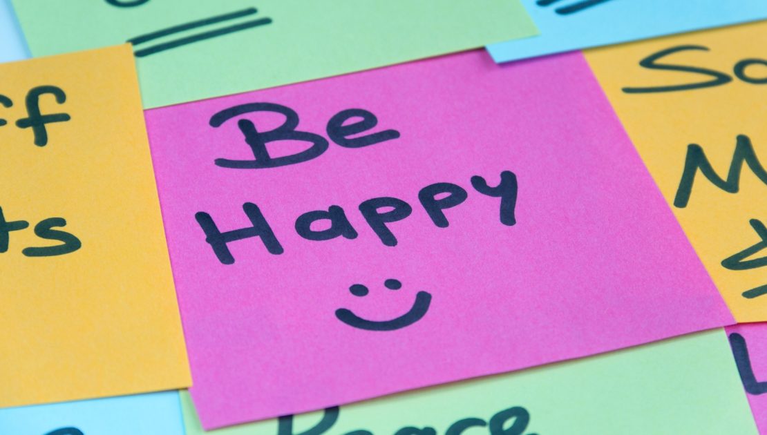A post it showing the message 'Be Happy :)'
