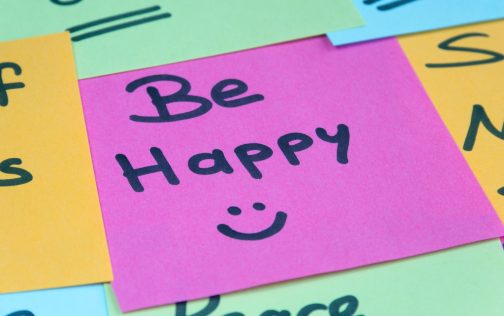 A post it showing the message 'Be Happy :)'